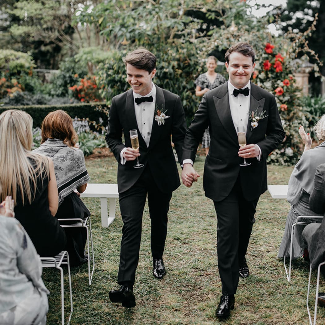 Photo of two men at their wedding ceremony in the Southern Highlands of NSW walking down the aisle outdoors.